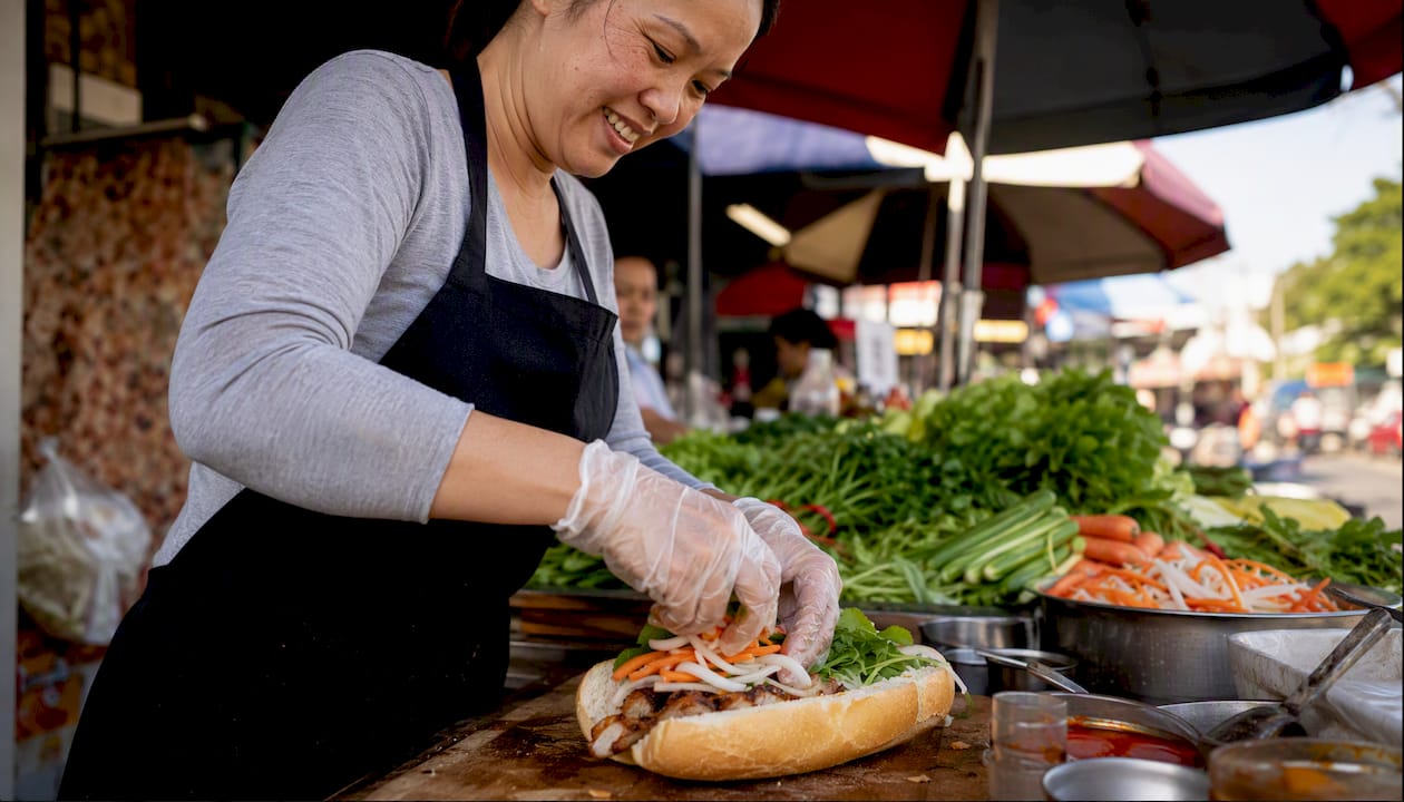 Vendor preparing bánh mì sandwich in Vietnamese market