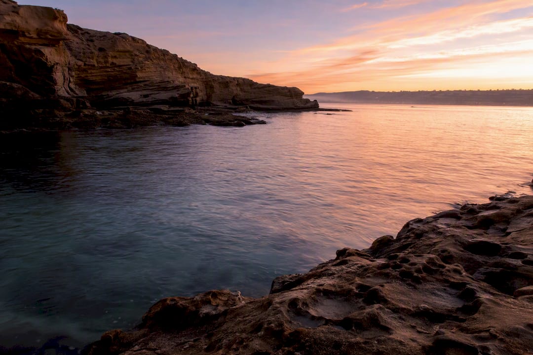 La Jolla Cove sunrise with mirrored water and cliffs