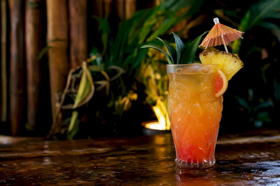Tropical tiki cocktail in jungle-themed bar interior