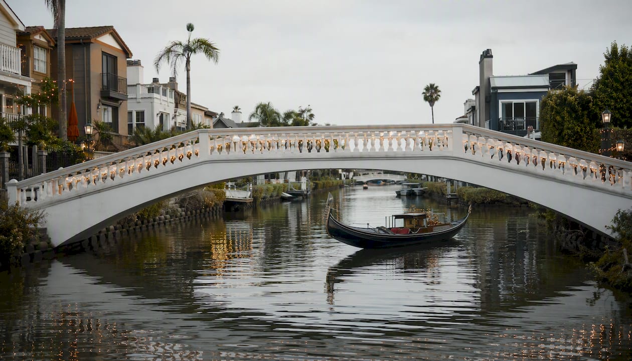 Gondola under Naples Canal arched bridge at sunset
