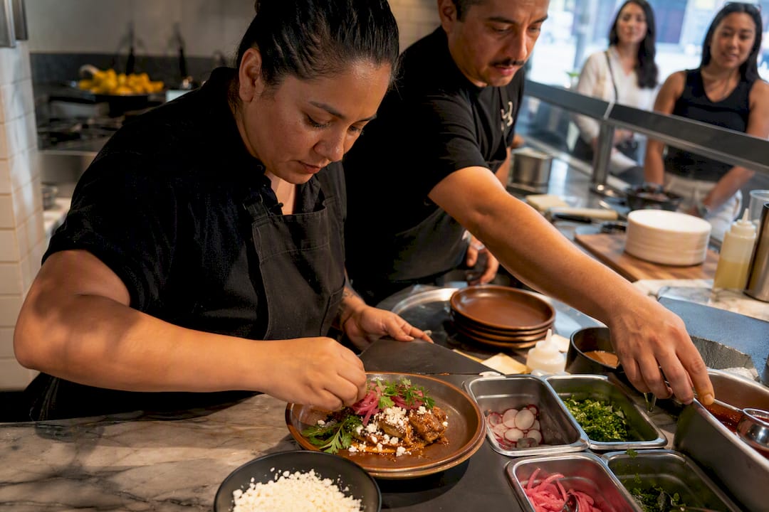 Family-run food stall preparing plated dish