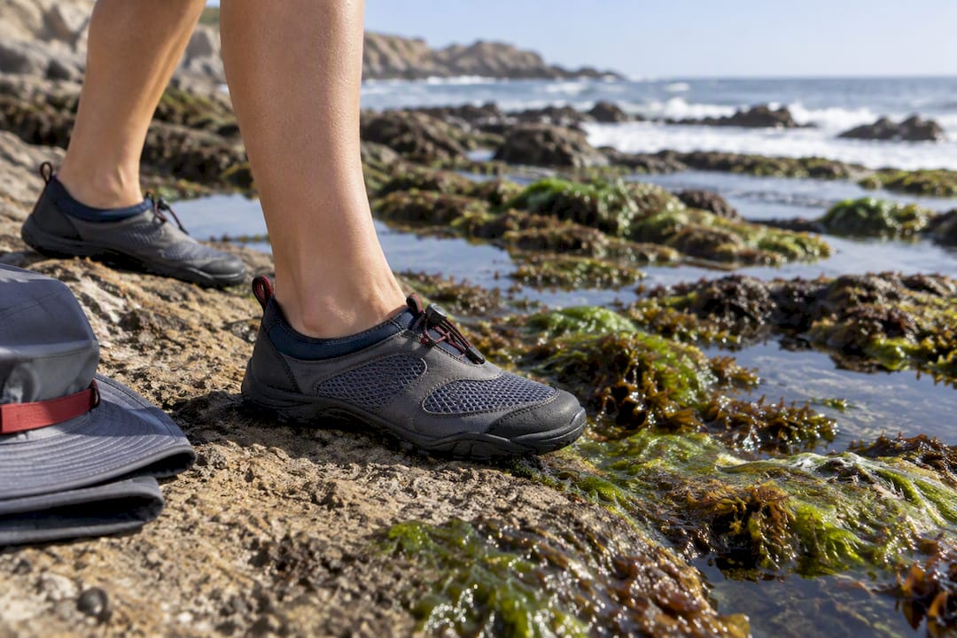 Closed-toe water shoes beside algae-covered rocks