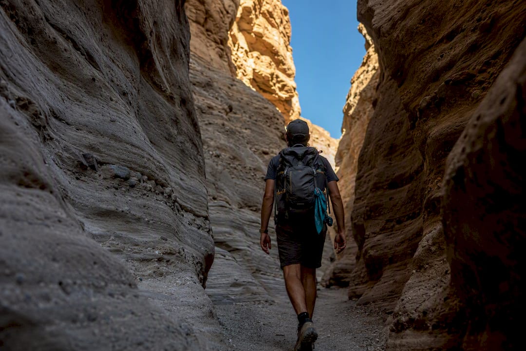 Hiker walking through narrow desert slot canyon