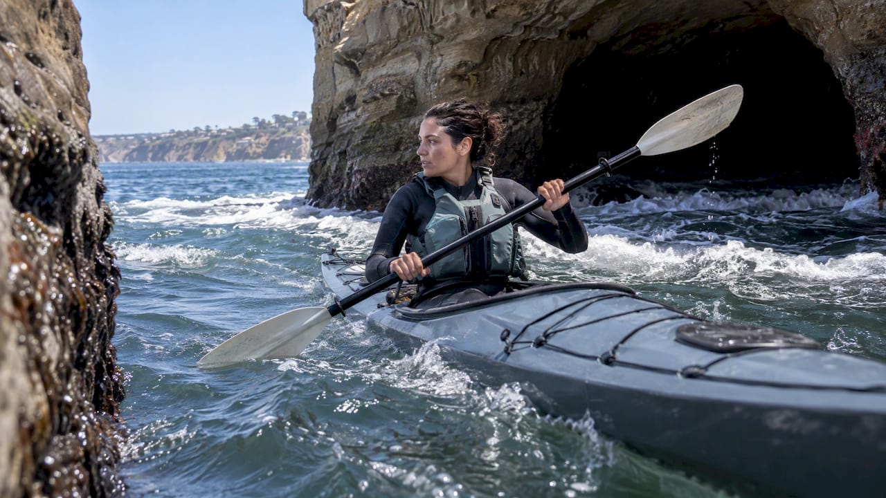 Kayaker moving away from surging cave entrance