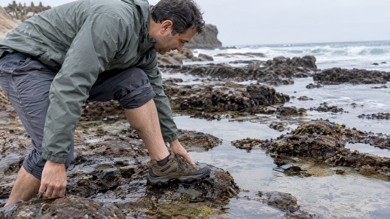 Hiker testing grip beside a tidepool